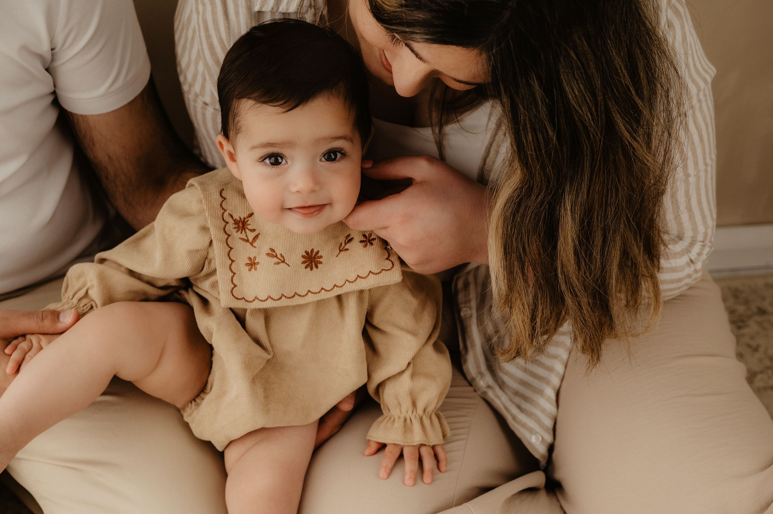 Intimate family portrait in neutral tones and soft lighting.