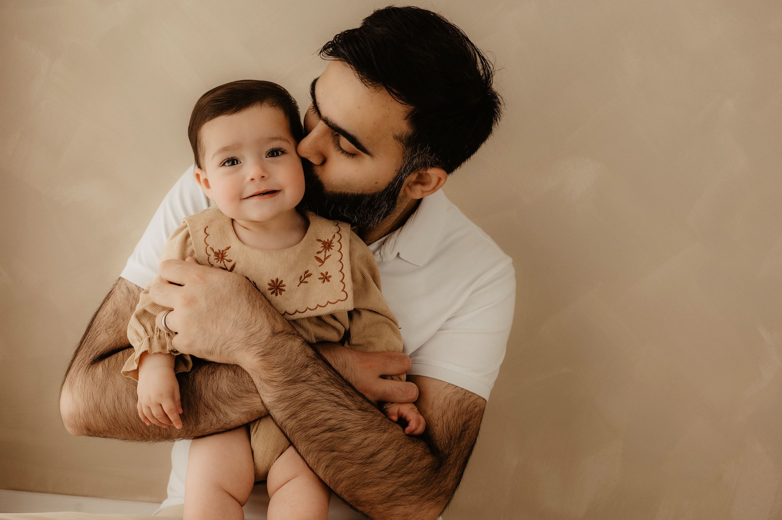 Loving family moment captured in warm sepia tones showing parent and baby sharing affectionate cuddle.