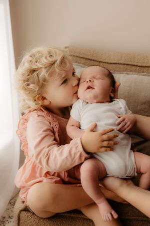 Two siblings share sweet bonding moments together on a beige sofa.