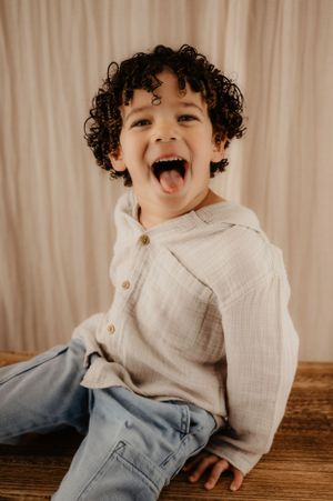 Joyful expression captured of a child with curly hair wearing a white shirt and jeans.