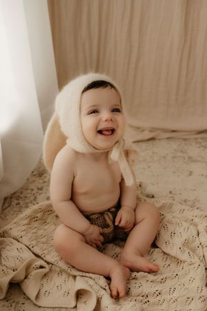Joyful baby explores and plays on textured cream blanket.