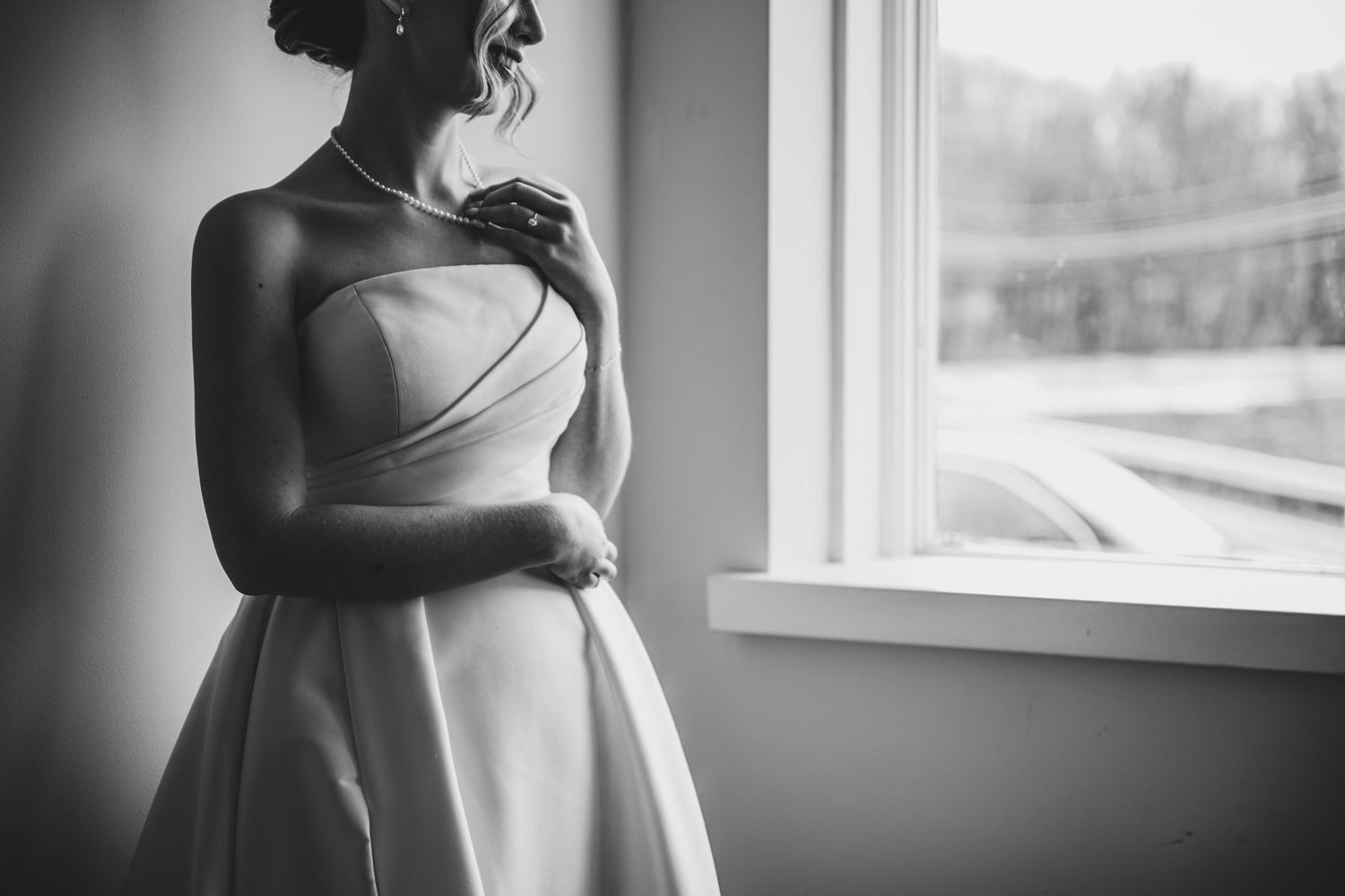 Black and white maternity photography series showing silhouetted figure by window in flowing dress.