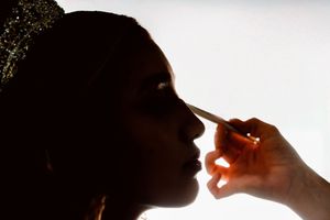 Makeup artist applying foundation with a brush to a woman's face in dramatic backlit silhouette. Charleston, Summerville,South Carolina