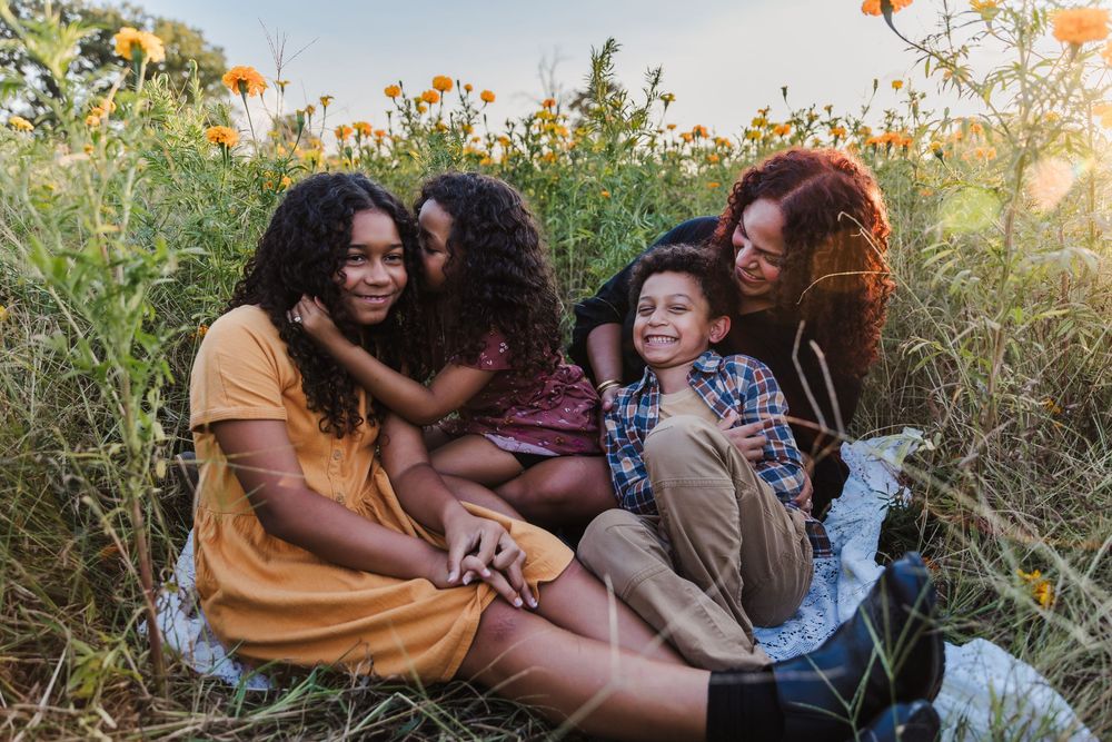 Group of friends sharing intimate moments in a field of flowers during golden hour.