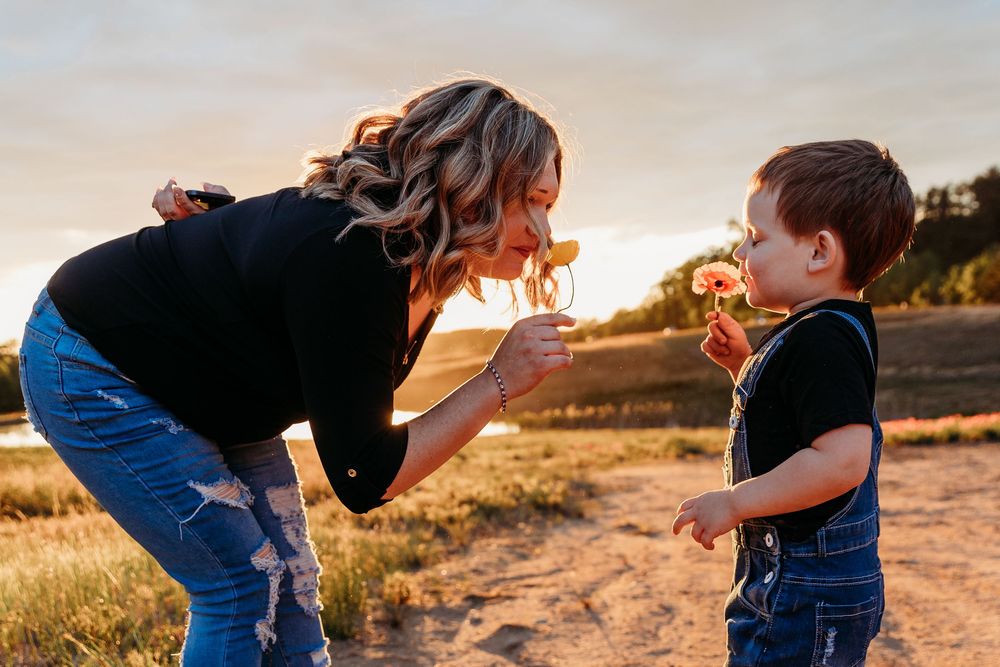 A mother and young boy share a joyful moment with lollipops outdoors at golden sunset hour.