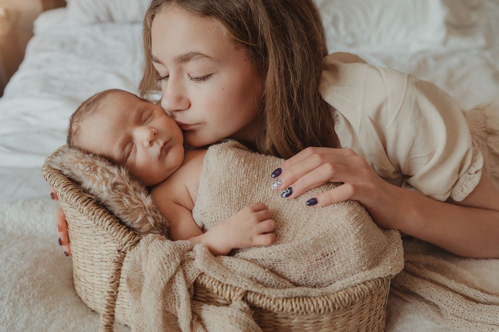 Sister cuddling newborn baby brother