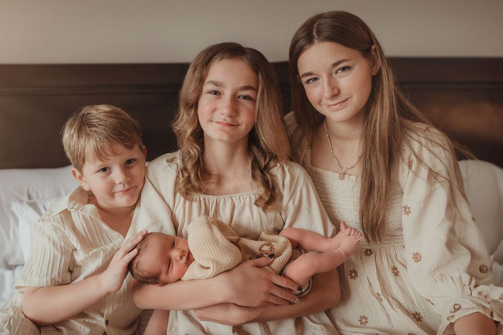 Family cuddling their newborn on a bed during a lifestyle session