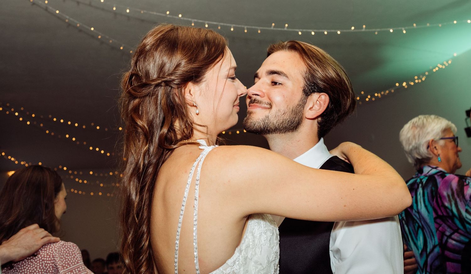 A bride in a white gown shares a joyful dance with the groom at their wedding reception.