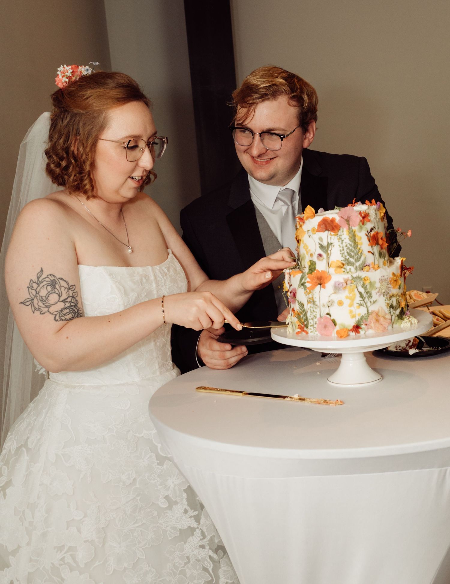 Bride and groom cutting a floral wedding cake together at their reception.