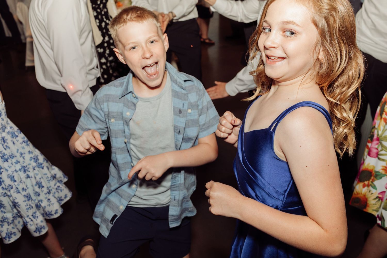 Two kids energetically dancing and having fun at a wedding reception.