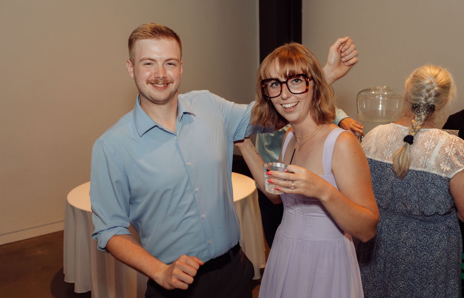 Smiling couple posing together at a wedding cocktail hour reception.