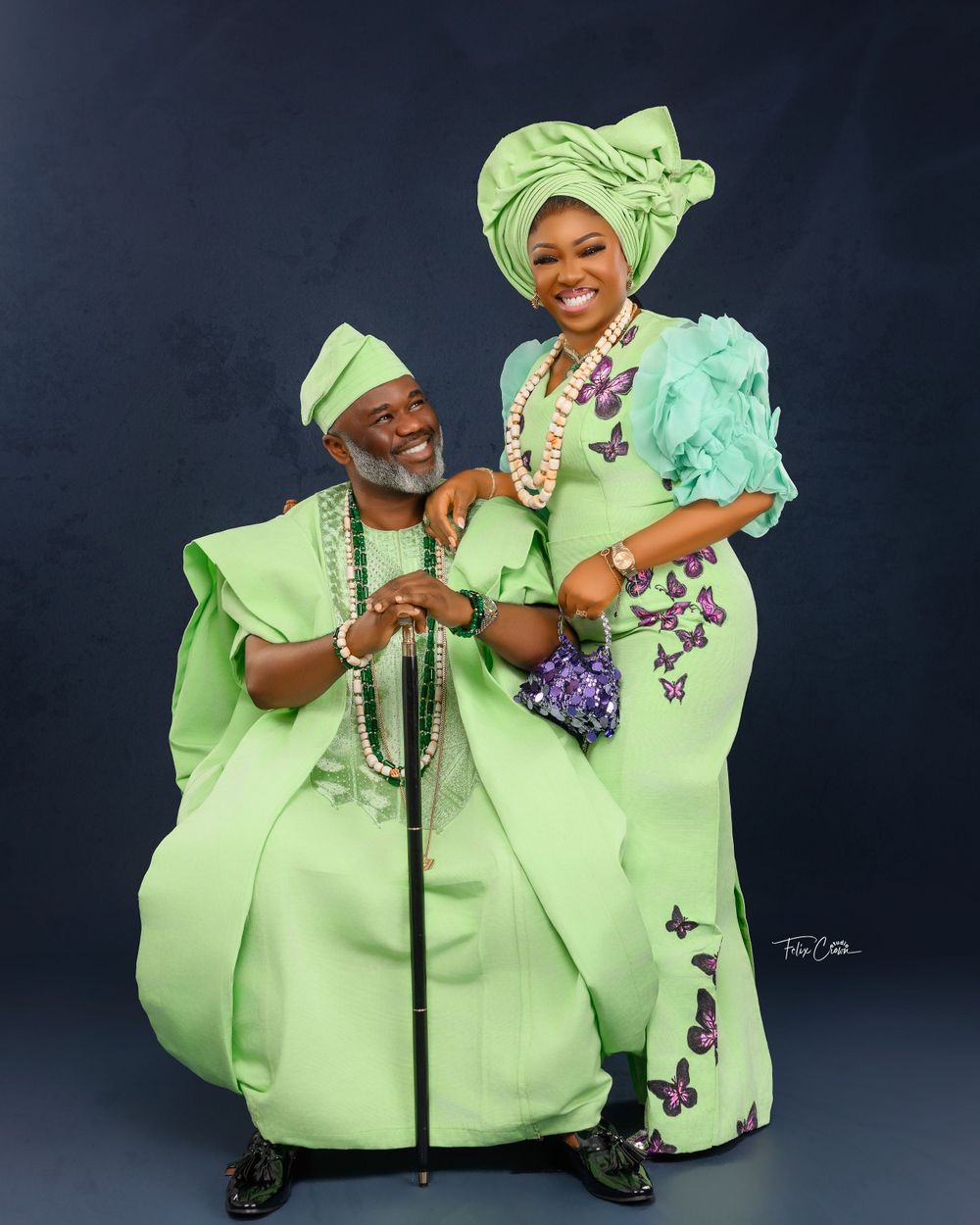 A couple wearing coordinated lime green traditional Nigerian attire poses together for a formal portrait.