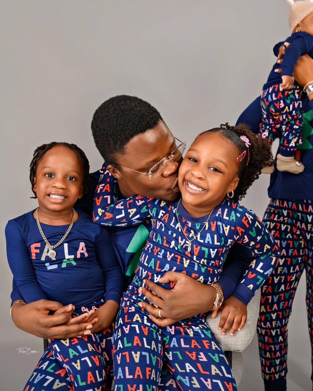 Joyful family portrait with matching navy and patterned outfits against studio background.