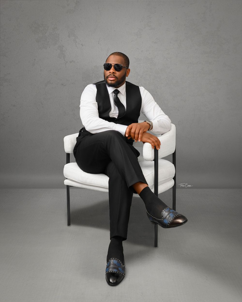 Business professional in vest and white shirt sitting in modern white chair.