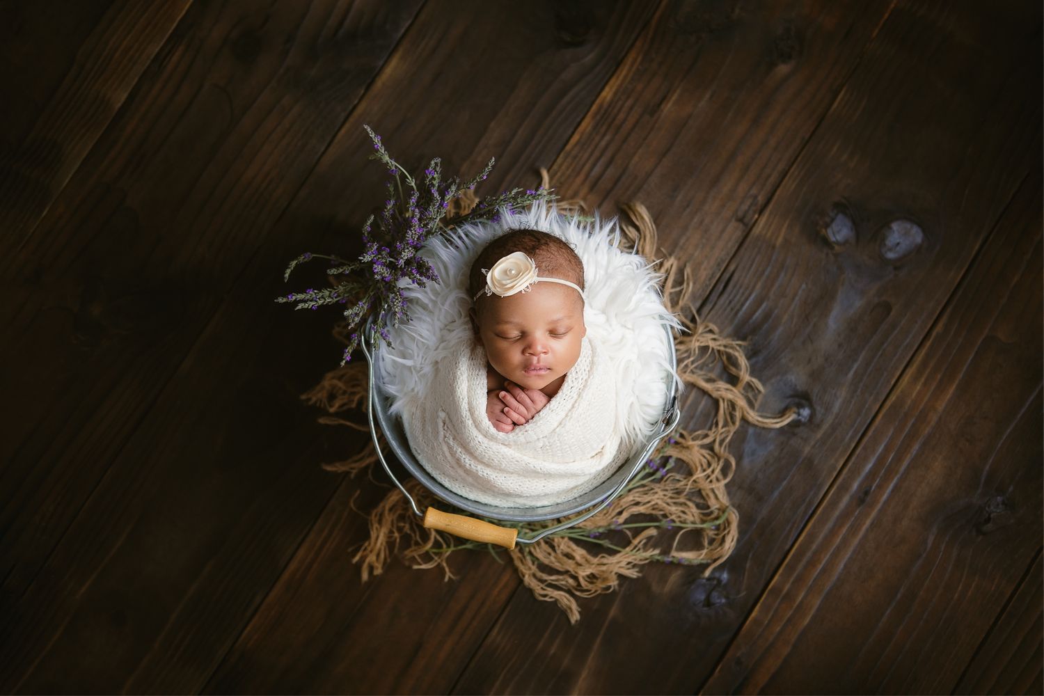 Studio newborn photography of a baby girl swaddled in a bucket with lavender flowers, photographed by Abigail Smith Photography in Empangeni