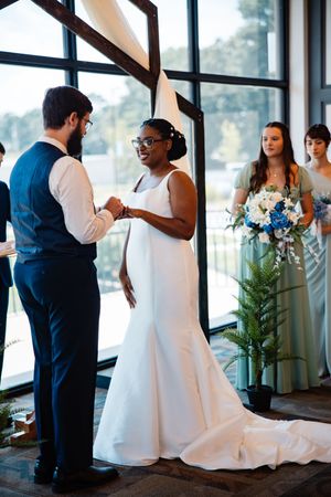 A wedding ceremony takes place in a modern venue with large windows.   Arkansas Wedding Photographer