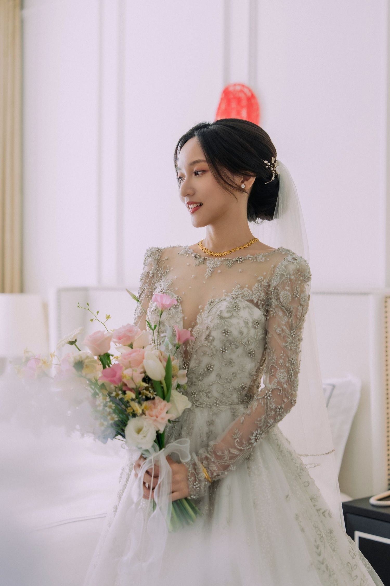 新娘穿白色婚紗，手持淡色捧花站在室內