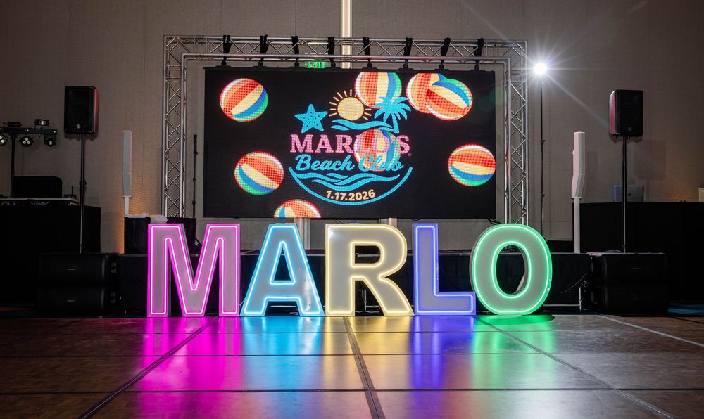 Glowing multicolor LED letters spell MARLO in front of a Marlo's Beach Bash screen with beach balls on an event stage.