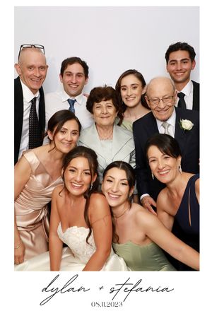 Wedding party poses together in formal attire for a portrait with mixed generations of family members.