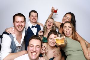 Group of wedding guests posing together while holding up drinks and celebrating.
