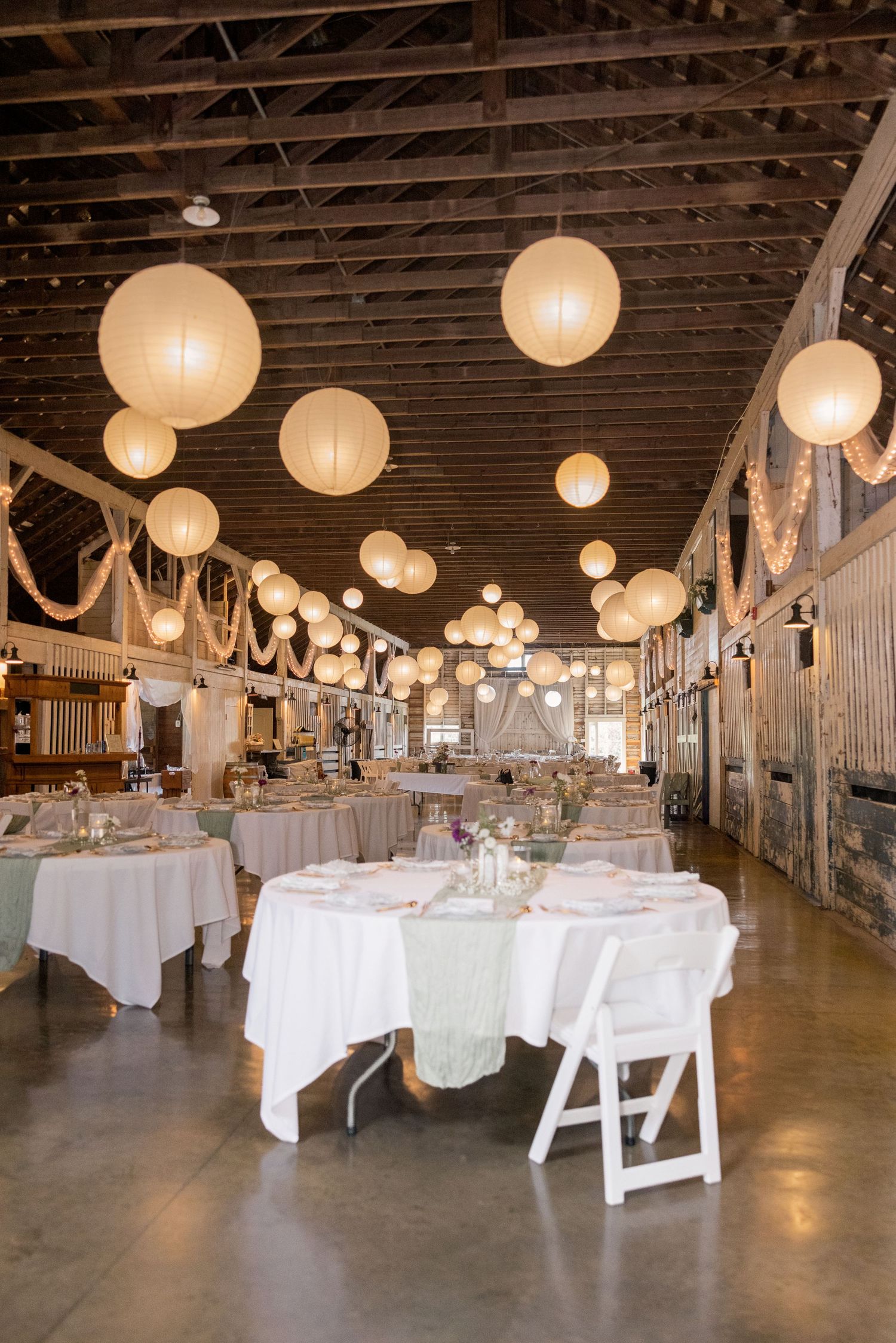 Lantern-lit barn reception with white linens and sage green runners at Little Brook Meadows in Lancaster, Ohio