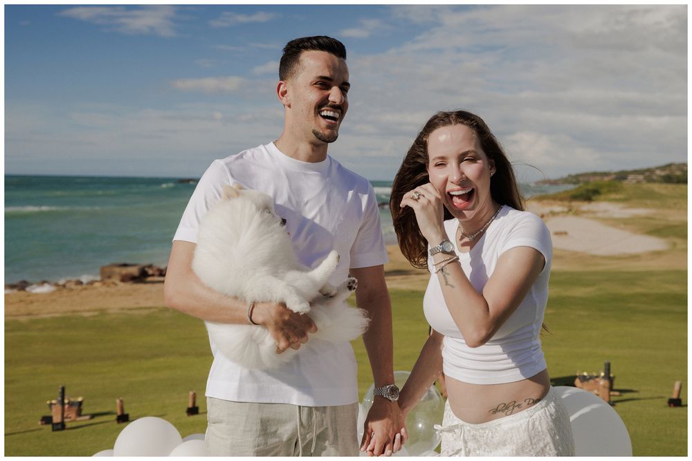 Beach family photo session at St. Regis Punta Mita, featuring a couple laughing together with their fluffy white cat on the oceanfront golf.
