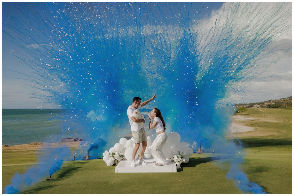 Gender reveal photoshoot at St. Regis Punta Mita, with a couple celebrating amid blue and pink powder by the ocean.