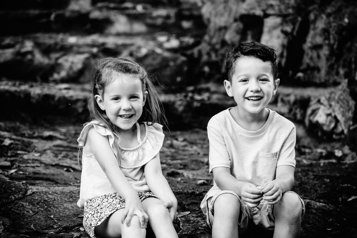 Black and white portrait of a brother and sister sitting together on stone steps.
