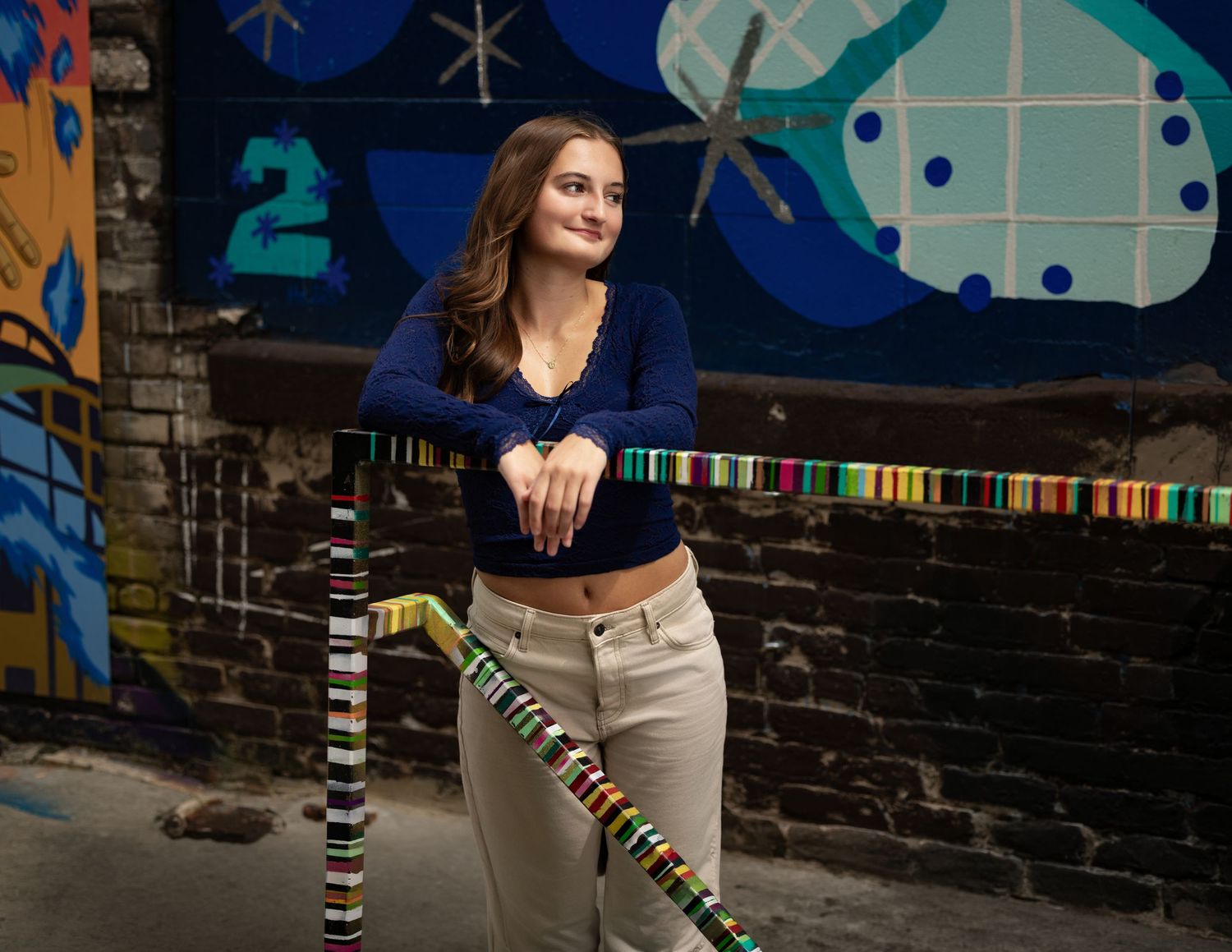 Senior portrait of a brunette girl posing in a colorful downtown setting