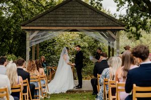Bride and groom exchange vows under a rustic gazebo at an outdoor wedding ceremony.