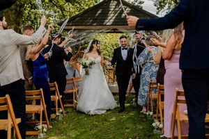 Bride and groom walk down aisle as guests celebrate with ribbon wands.