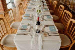 Elegant wedding reception table set with white linens, blue napkins, and a red wine bottle.