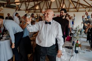 Man in bow tie raises champagne glass in toast at elegant wedding reception celebration.