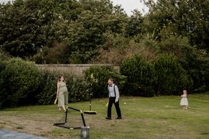 Wedding guests playing lawn games in a lush green garden during an outdoor wedding reception celebration.