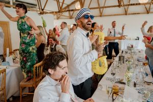 Guests dancing and celebrating at a lively wedding reception in a rustic venue.
