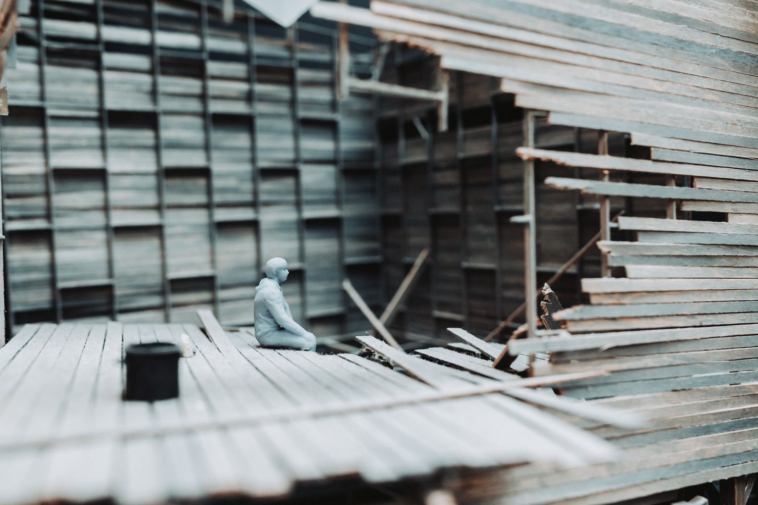 Worker sorting lumber planks at a wood yard construction site surrounded by stacked timber boards.