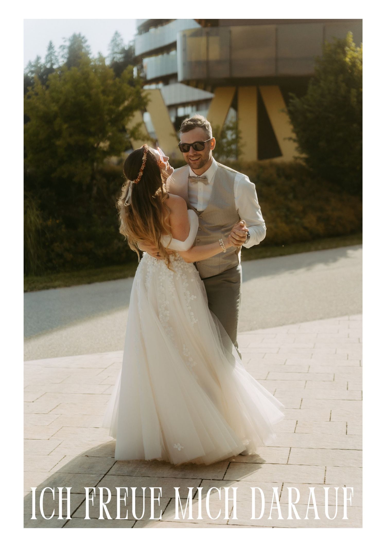 A couple shares a romantic dance outdoors on their wedding day, bride in white gown and groom in gray suit.