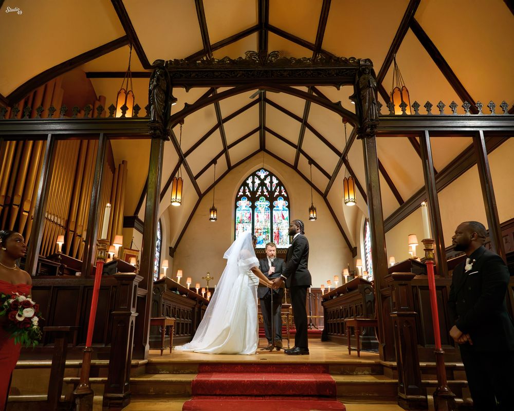 Elegant wedding ceremony inside a traditional church with Gothic architecture, couple exchanging vows at the altar.