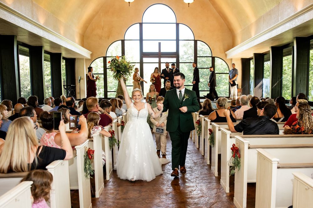 Joyful newlyweds walk down the aisle in a charming chapel, surrounded by cheering guests after their wedding ceremony.
