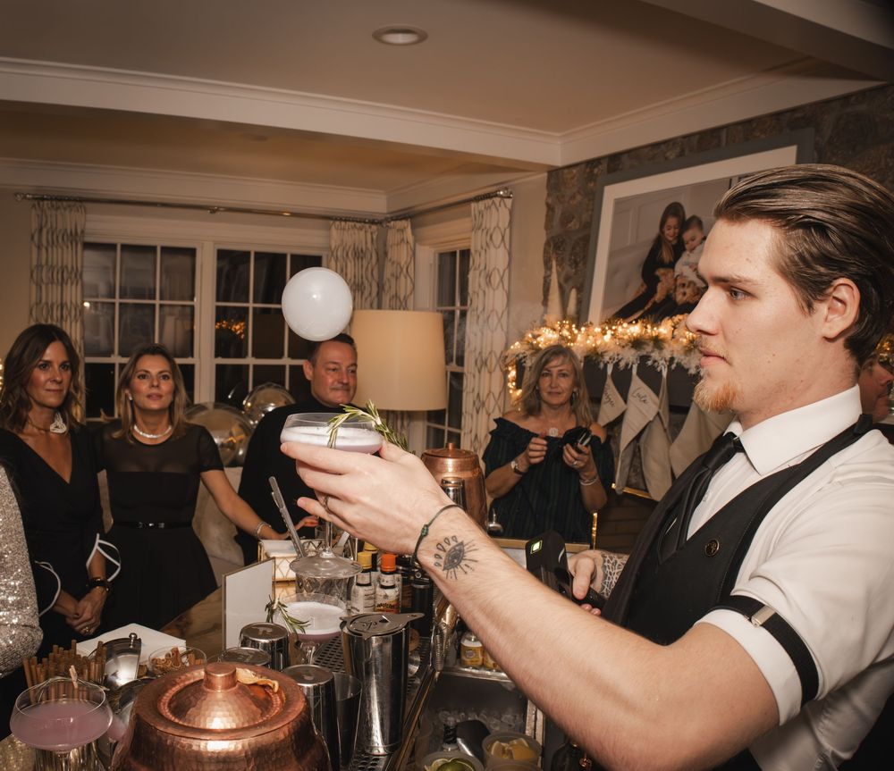 A bartender creates a sparkling cocktail display for guests at an elegant evening party.