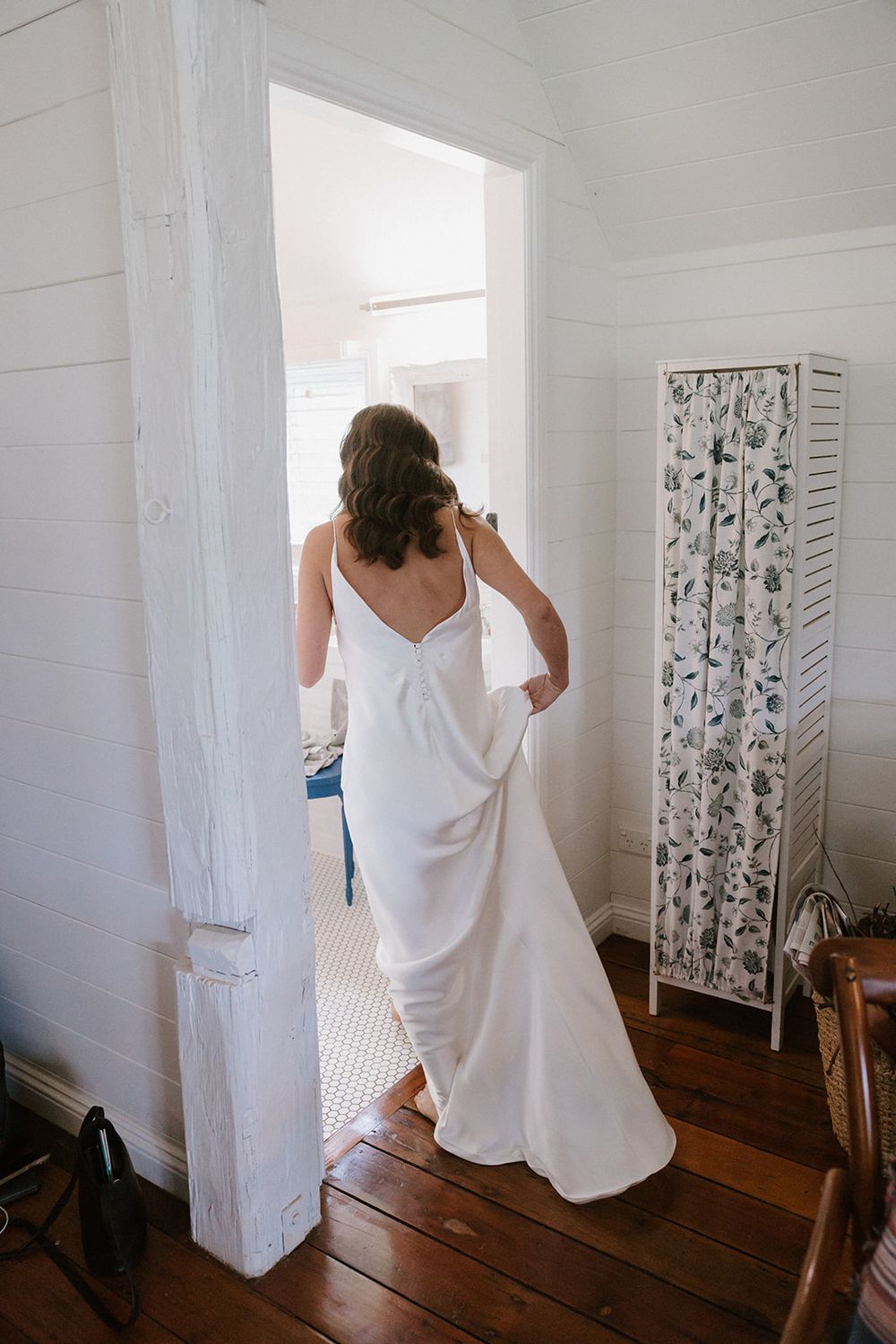 Sequential images of someone adjusting white clothing near a decorative room divider on hardwood floors.