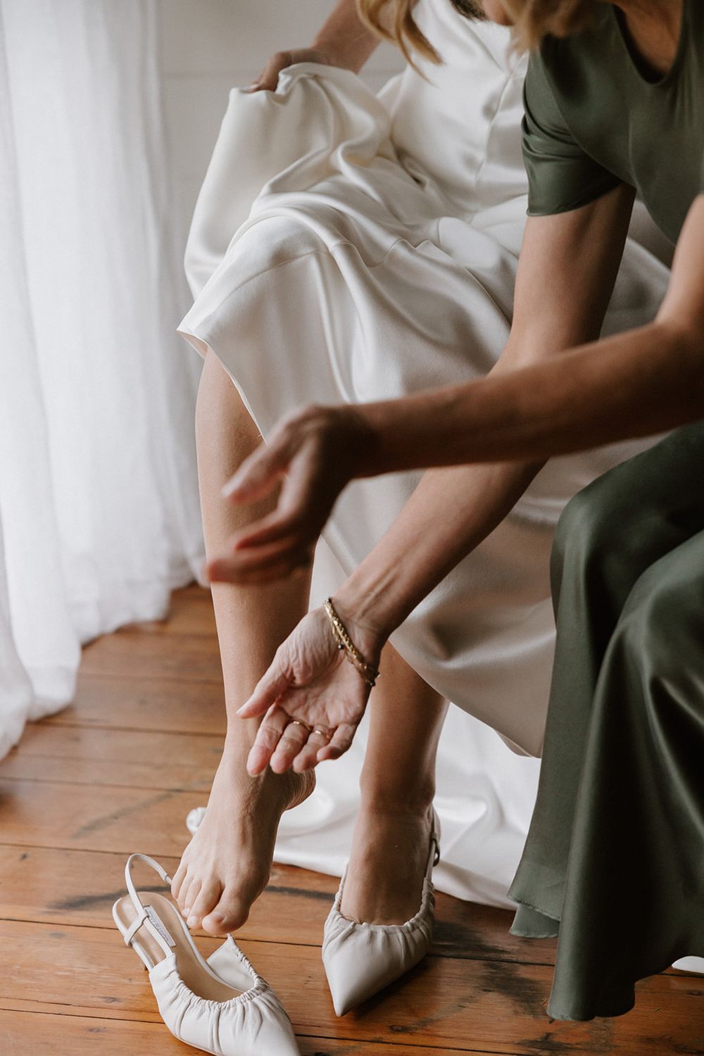 A sequence showing white ballet flats being fitted on feet against a wooden floor.