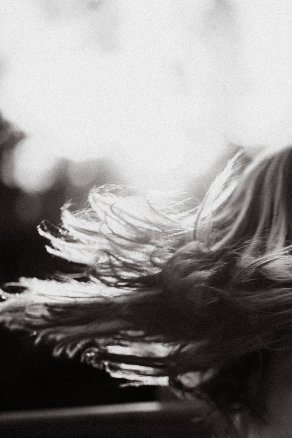 Black and white photo of long hair blowing in the wind, captured in motion blur.