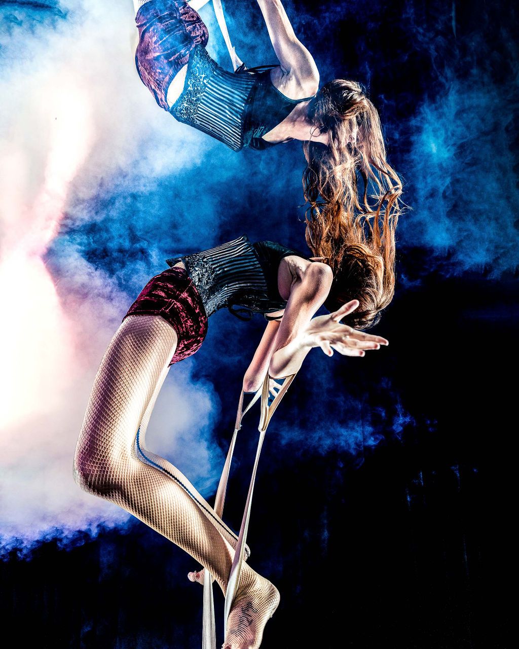 a female trapeze performer hanging over a mirror in a mind-bending portrait