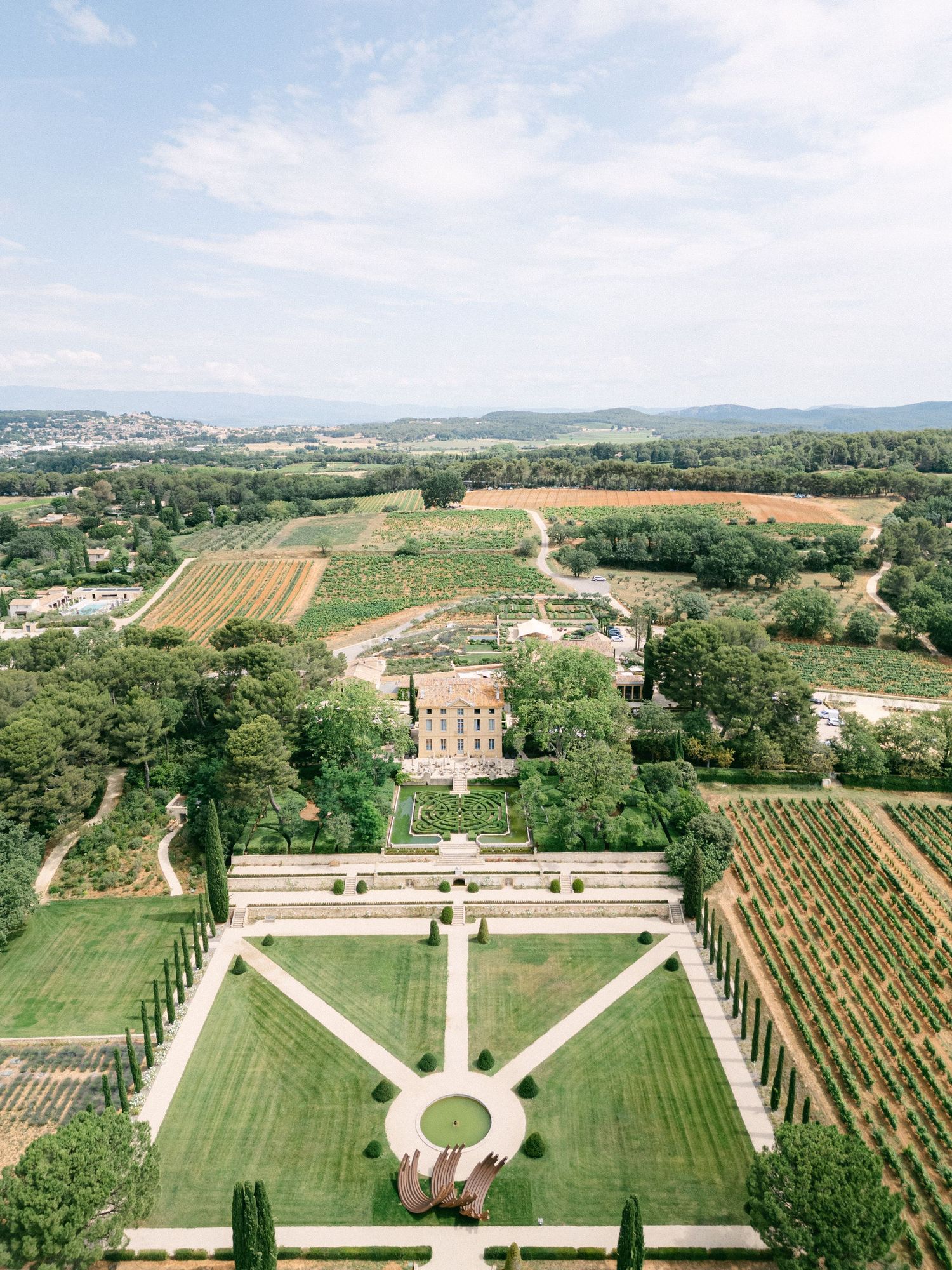 Aerial view of an intricate green hedge maze with circular and Celtic knot patterns in a formal garden.