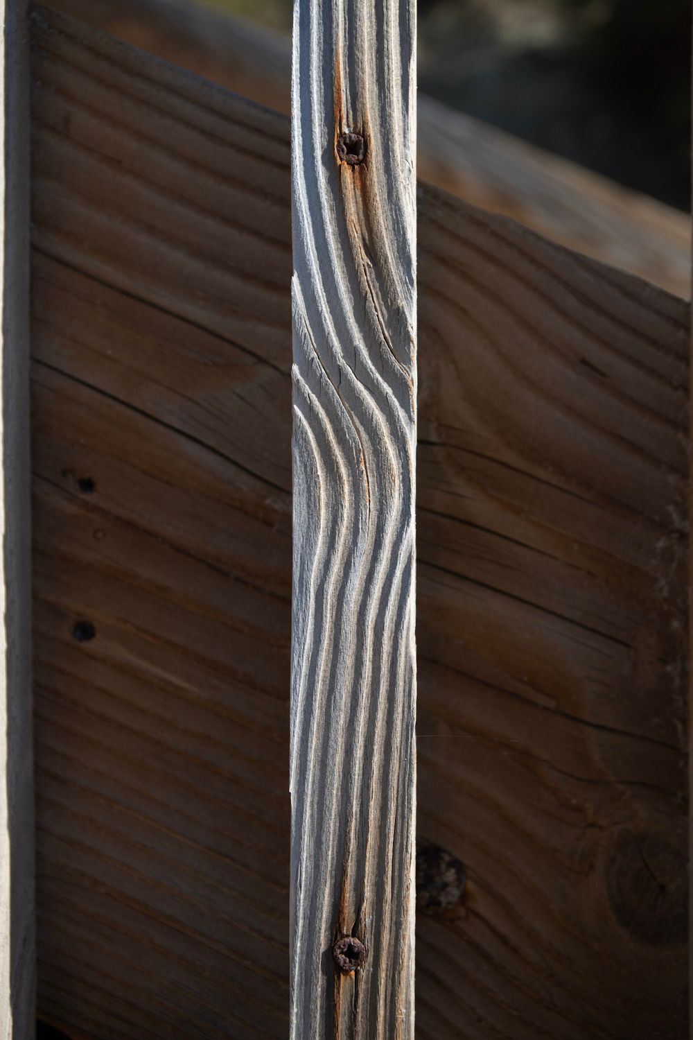 Close-up of weathered wooden planks with natural grain patterns and rusty nails, showing aged texture and detail.