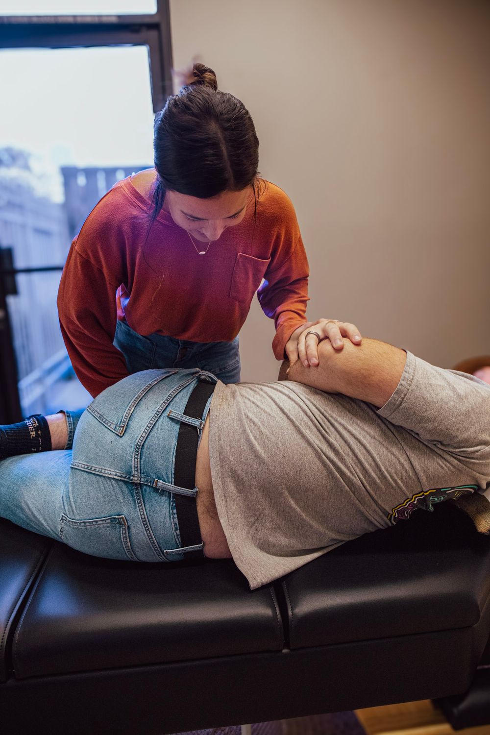 Chiropractor performing a spinal adjustment on a patient lying on a treatment table in a clinical setting.