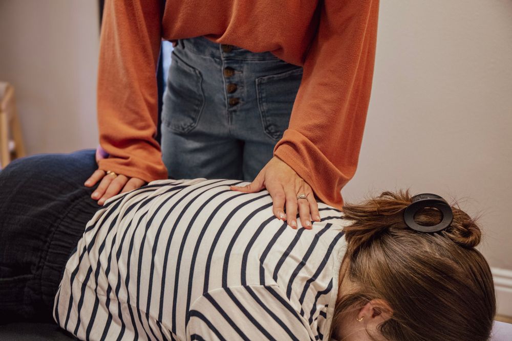 Chiropractor performing a back adjustment on a patient lying face down on a treatment table.