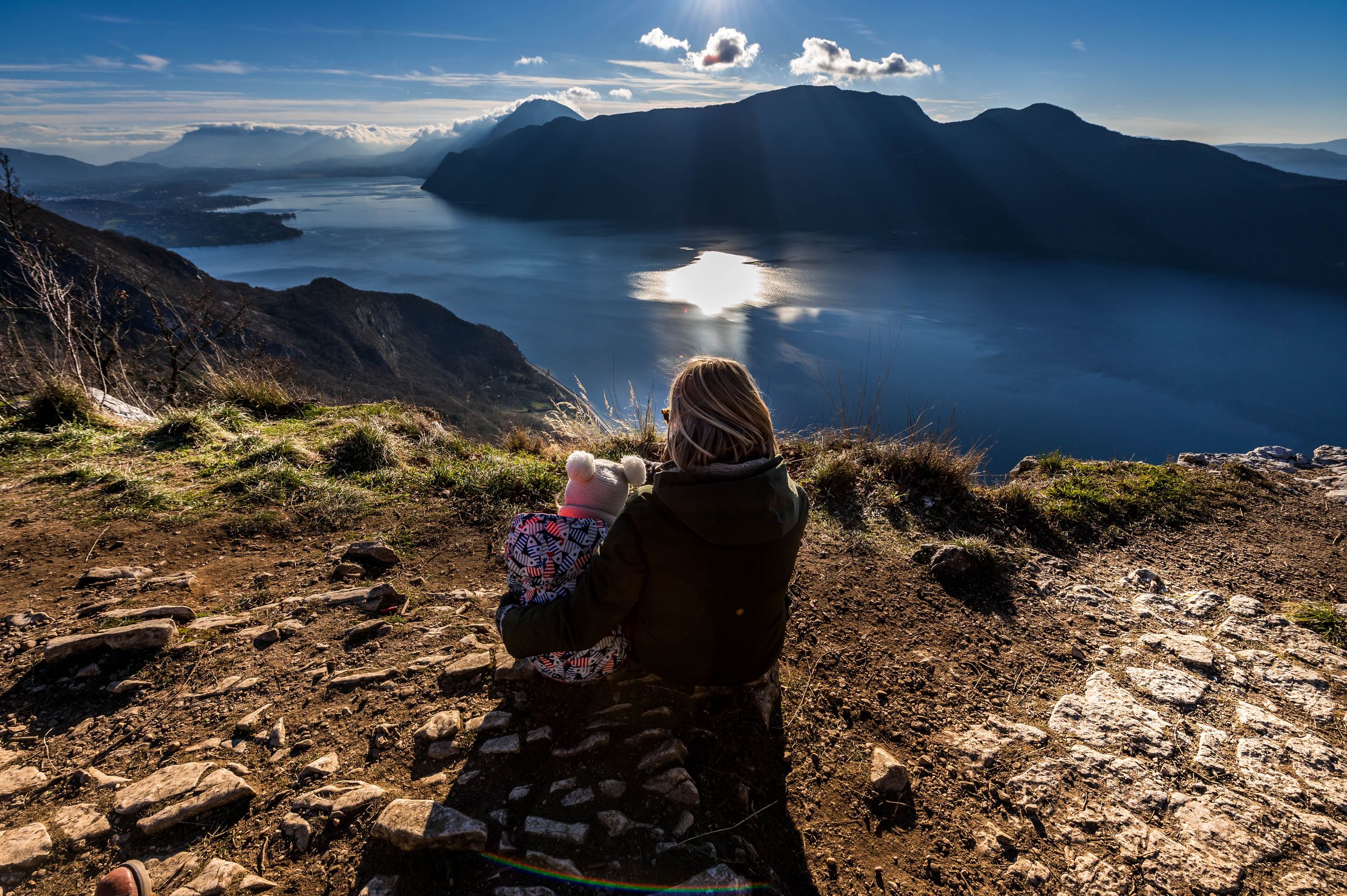 Mère et enfant admirant un lac entouré de montagnes lors d’une randonnée