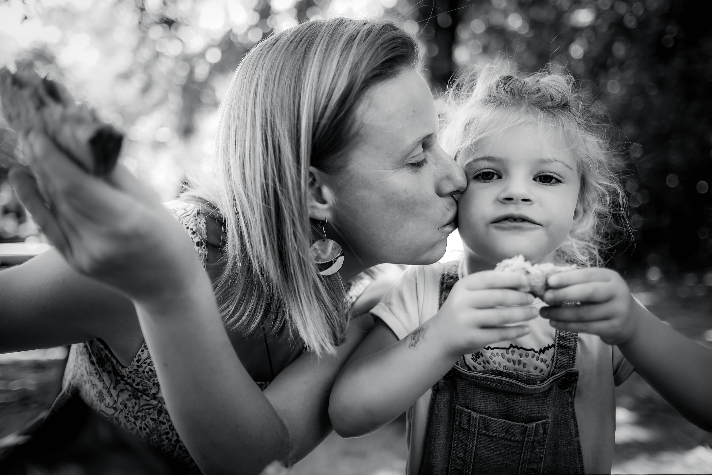 Mère embrassant son enfant lors d’une séance photo famille en extérieur